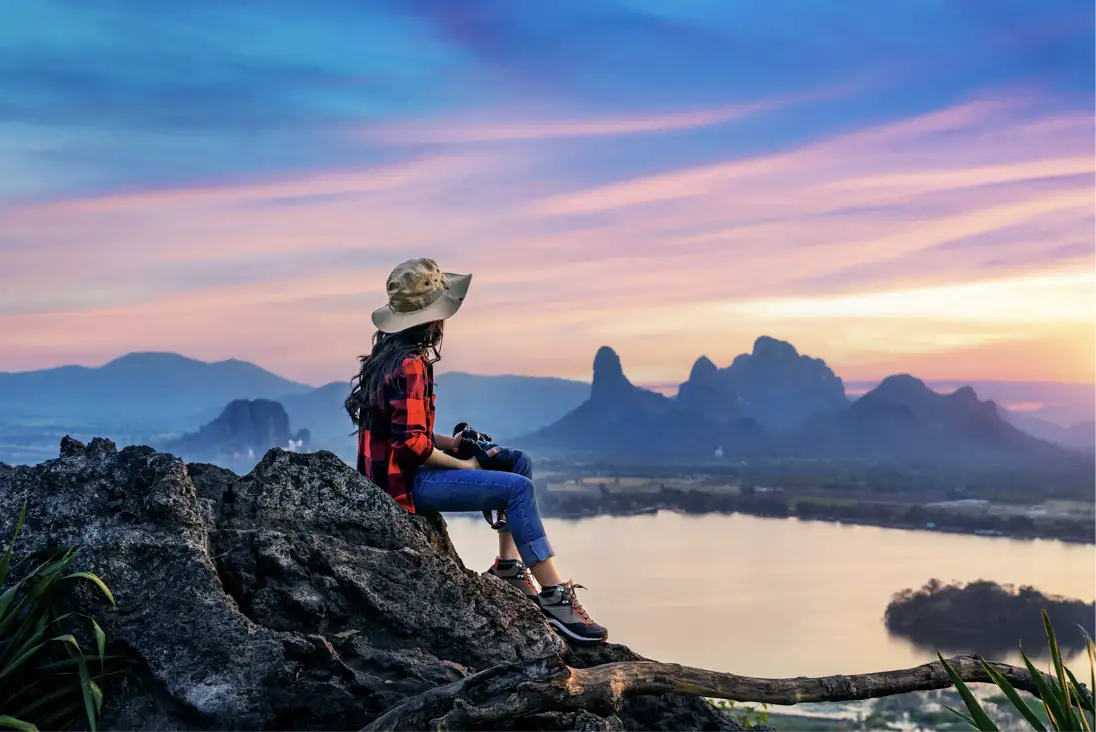 Traveler on a mountain at sunset with camera